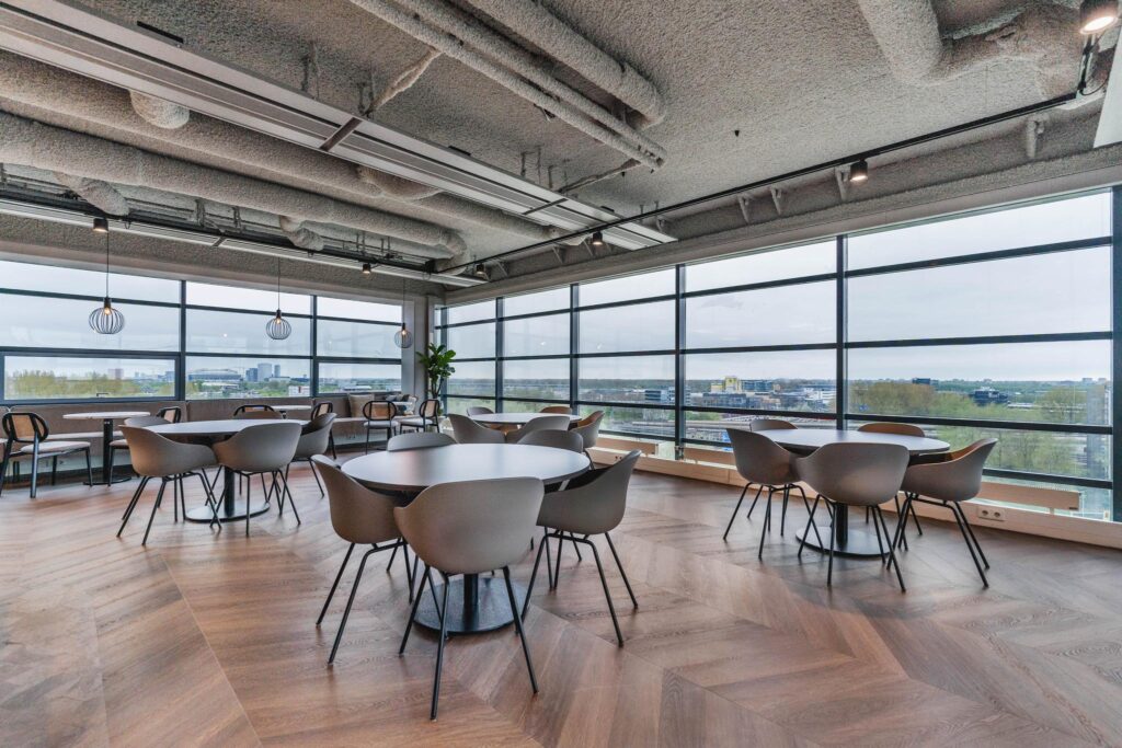 Modern office dining area on Joop Geesinkweg with large windows and a city view.